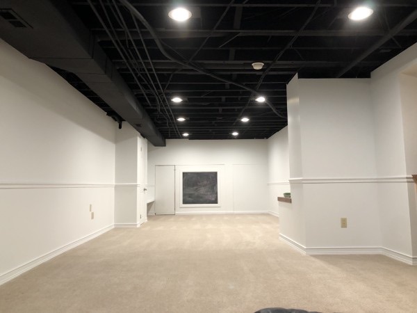 Finished basement with a black painted open ceiling and light walls