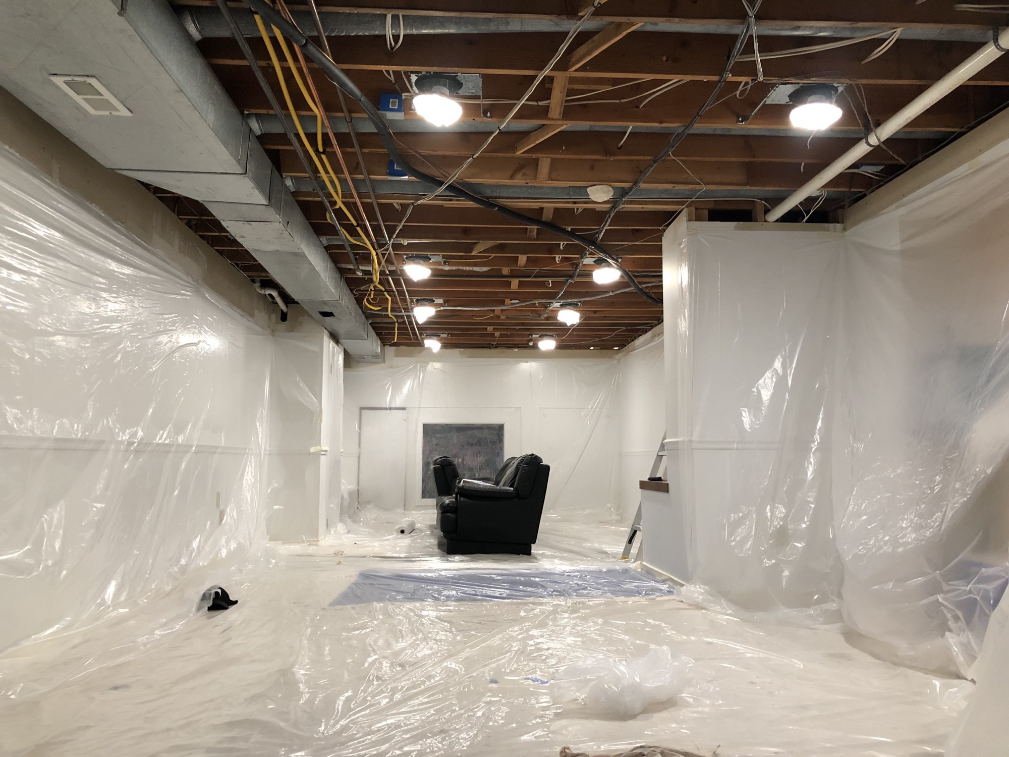 Basement walls, floors, trim, and furnishings protected before ceiling painting