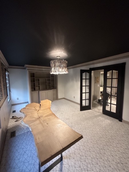 Finished dining room with a black ceiling, light walls, built-ins, and black French doors